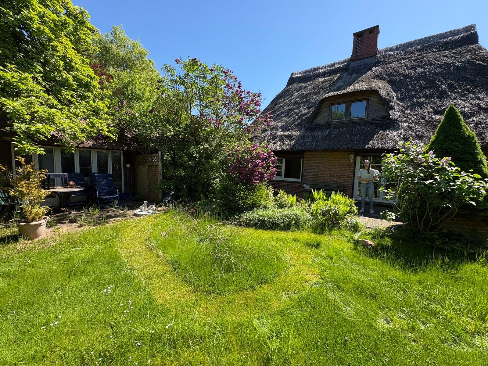 Terrasse mit Gartenmöbeln und Blick auf die Reetdach-Kate